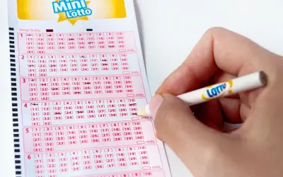 Ręka zaznacza liczby na kuponie Mini Lotto. To kaskada zasady, gdzie każda kolejna linijka to szansa na wygraną.