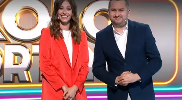 Uśmiechnięta kobieta w czerwonej marynarce i mężczyzna w granatowym garniturze na tle logo "Koło Fortuny".
