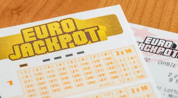 Kupony gry Eurojackpot z polami do zaznaczania liczb na drewnianym tle.