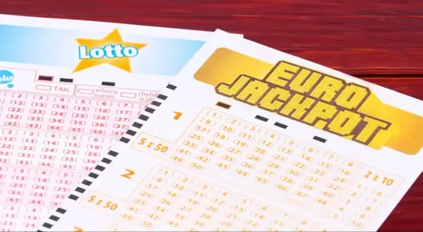 Kupony Lotto i Eurojackpot, do której wysyłamy eurojackpot, leżą na drewnianym stole.
