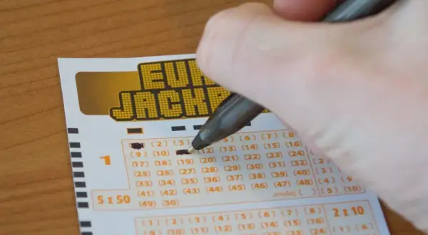 Dłoń zaznacza liczby na kuponie Eurojackpot. Zastanawiasz się, jak skreślić Eurojackpot? To proste!