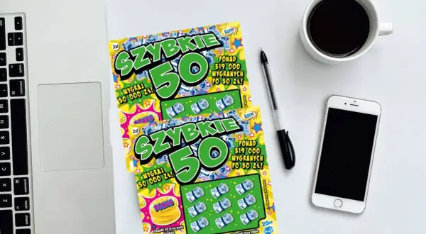 Dwie zdrapki "Szybkie 50" leżą obok laptopa, telefonu i kawy. Dowiedz się, jak sprawdzić zdrapkę i czy masz szczęście!