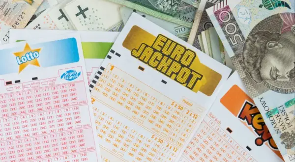 Kupony Lotto i Eurojackpot leżą na stosie banknotów. Zastanawiasz się, ile jest do wygrania w Eurojackpot dzisiaj?